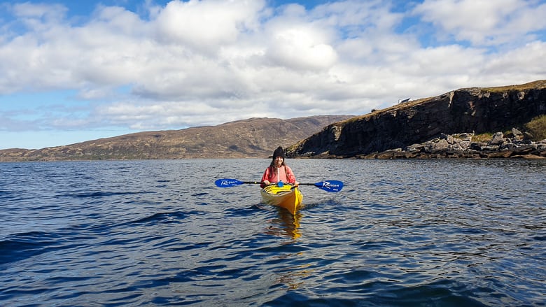 A woman in a floating sea kayak posing for a photo 
