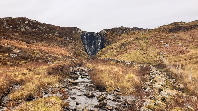 A small stream with a waterfall in the distance in a village of Clashnessie